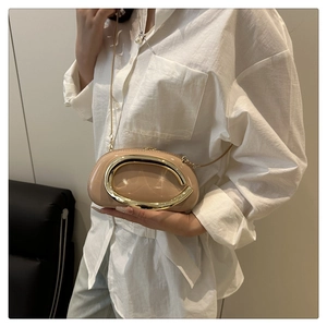 Close-up of beige patent leather pillow bag with a prominent gold C-shaped metal buckle