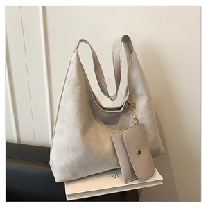Detail of grey matte suede hobo bag with matching mini pouch and leather handle on books
