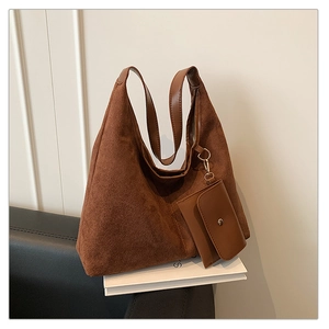 Detail of dark brown matte suede tote bag with matching mini pouch on white books