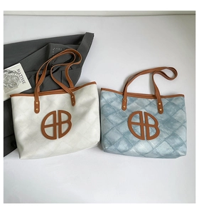 Flat lay of cream and blue quilted tote bags with brown leather handles and logo detail