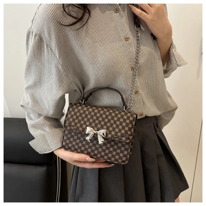 Detail of vintage brown polka dot shoulder bag with silver metal bow and chain strap