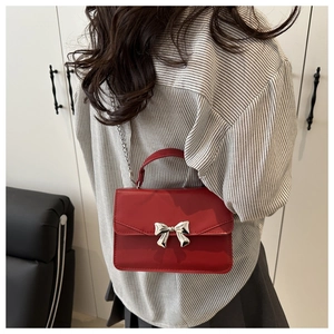 Detail of red mini crossbody bag with silver bow buckle and metallic chain strap