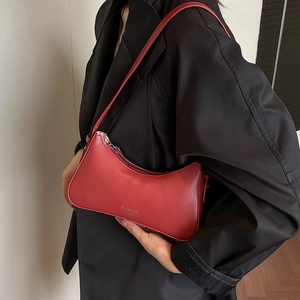 Red lychee pattern shoulder bag shown on model with black suit for elegant contrast