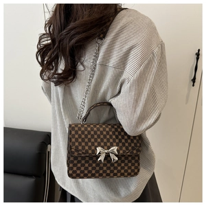 Brown crossbody bag with circle patterns, silver bow buckle, and chain strap detail
