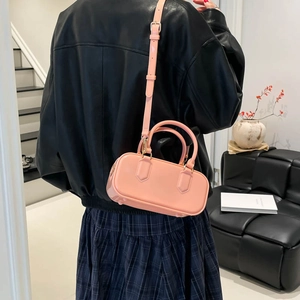 Pink Boston style jelly handbag with adjustable strap worn by a model in black jacket