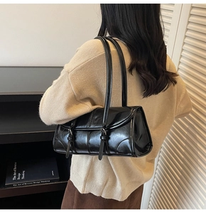 Detail view of black glossy shoulder bag featuring stylish strap buckles and rectangular flap