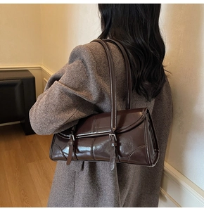 Detail view of deep brown oily leather shoulder bag with metallic buckle strap accents