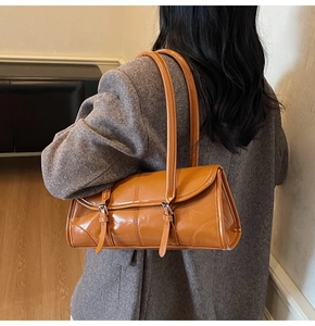 Close-up of caramel leather baguette bag showing glossy texture and strap details