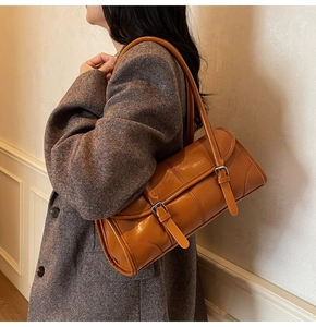 Detail of caramel oil leather shoulder bag showing glossy texture and buckle straps