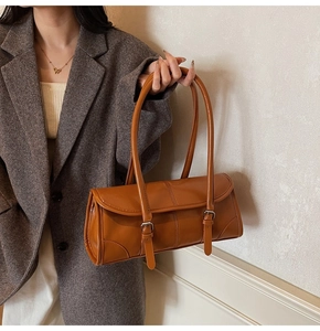 Close-up of caramel brown leather baguette bag with silver buckle and sleek texture