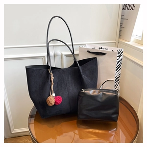 Detail of black suede tote bag and small PU pouch with colorful faux fur pompom charm