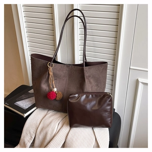 Detail of dark brown suede tote bag with plush pom-poms and matching inner pouch