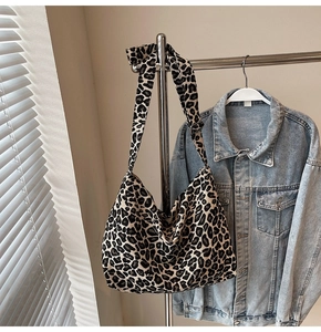 Close-up of leopard print canvas bag with adjustable wide strap on a denim jacket