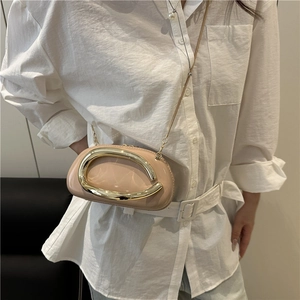 Minimalist beige leather crossbody bag with oversized gold oval handle and chain strap