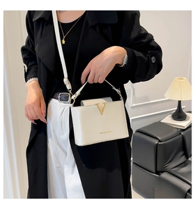 Detail of white leather crossbody bag featuring a gold V-clasp and fashion logo