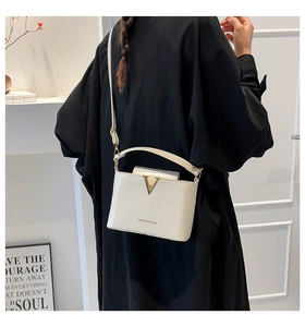 Fashionable beige crossbody bag with gold V-buckle shown on model from the back view
