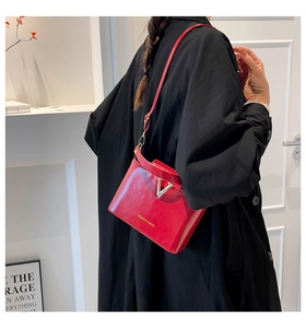 Detail of red crocodile pattern handbag featuring a luxury gold V-shaped metal clasp