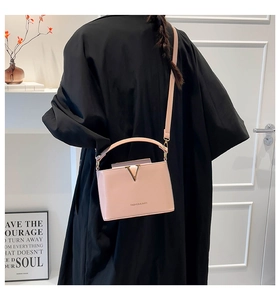 Detail of light pink crossbody bag with gold V-decoration and fashion lettering on back