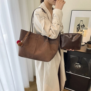 Brown minimalist tote bag with plush charm and matching clutch for urban style