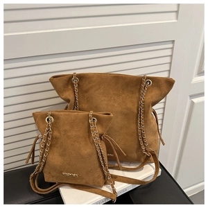 Close-up of brown suede bucket bags with gold chain straps and metal fashion lettering