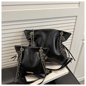 Detail of black leather bucket bag set with gold chain strap and fashion metal logo