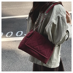 Model wearing a burgundy quilted chain strap shoulder bag against a street background