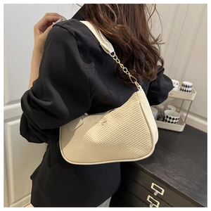 Detail view of cream white crescent shoulder bag with woven texture and chain strap