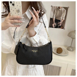 Detail of black crescent shoulder bag featuring textured finish and gold chain strap