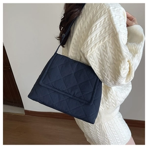 Detailed view of quilted nylon crossbody bag with diamond stitching on model in white sweater