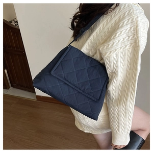 Close-up of diamond quilted crossbody bag in dark blue nylon with matching strap