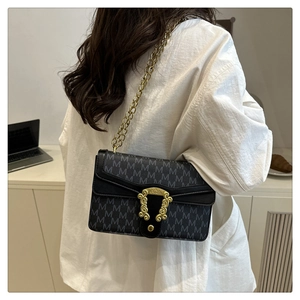 Detail view of black crossbody bag with M-pattern print and vintage gold buckle