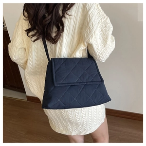Model wearing dark navy quilted crossbody bag with diamond stitch nylon texture