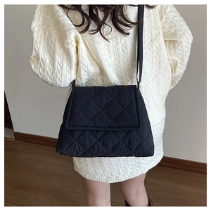 Detail of black quilted crossbody bag showing rhombus texture and shoulder strap fit
