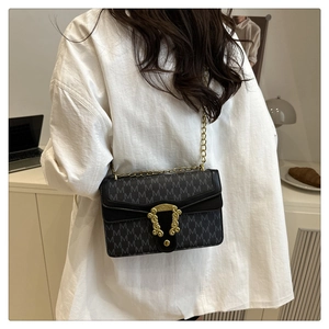 Close-up of black crossbody bag with golden Baroque lock and M-pattern print for women