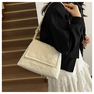 Side view of a beige quilted nylon crossbody bag featuring a soft padded flap and wide strap