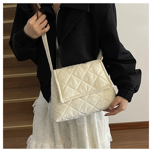 Model wearing a cream nylon quilted crossbody bag with stylish diamond stitch pattern