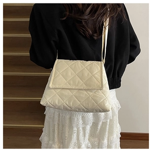 Quilted nylon crossbody bag in off-white shown on a model with a black jacket
