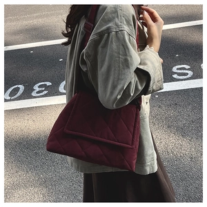 Detail of burgundy quilted nylon crossbody bag with diamond stitching and wide strap