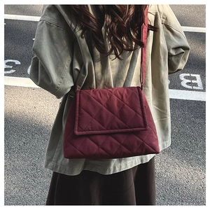 Detail of burgundy quilted nylon crossbody bag featuring elegant rhombus stitching texture