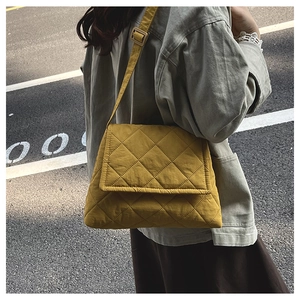 Close-up of bright yellow quilted nylon crossbody bag with adjustable strap and stitching