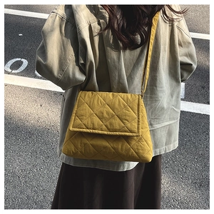 Close-up of mustard yellow quilted crossbody bag with diamond stitching and long strap