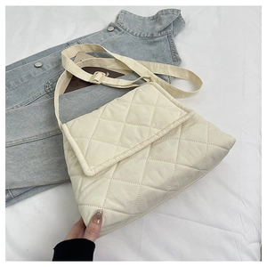 Detailed view of beige quilted crossbody bag with adjustable strap on denim jacket