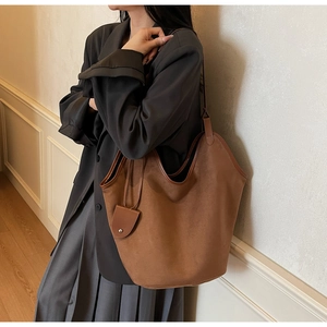 Brown suede tote bag shown on model's shoulder featuring minimalist large capacity design
