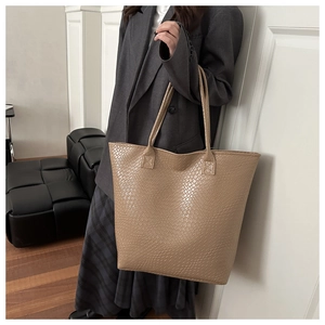 Detail view of light brown tote bag featuring elegant crocodile pattern and long straps