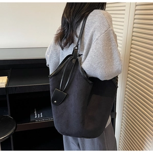 Black suede tote bag shown on model featuring a large capacity minimalist bucket design