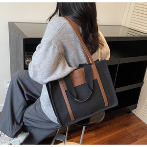 Canvas and leather tote bag styled on model in an elegant indoor setting with warm lighting