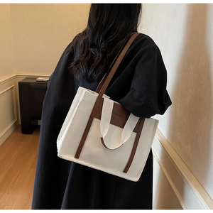 Detailed view of the large canvas tote bag with brown leather trim and dual handles