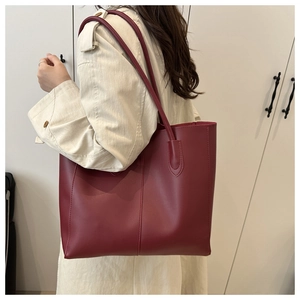 Grand sac cabas en cuir bordeaux porté avec un trench-coat classique de couleur beige