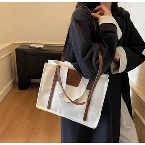 Close-up of large canvas tote bag with brown leather trim and FASHION & BAG lettering