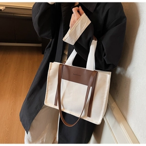 Detail of large canvas tote bag with brown leather handles and adjustable shoulder strap